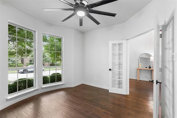a view of empty room with wooden floor and fan