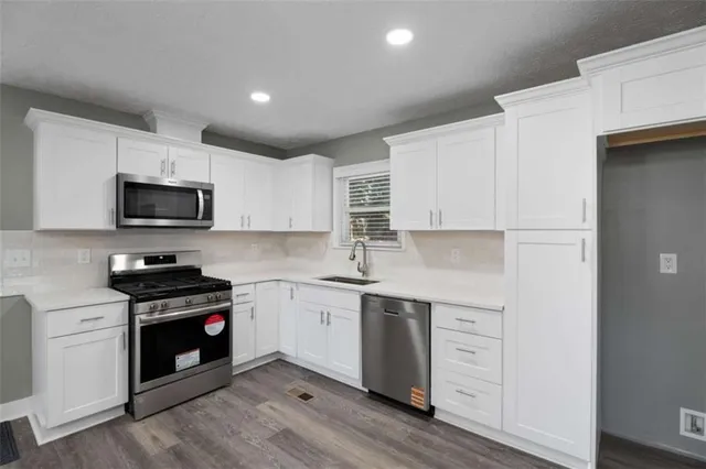 a kitchen with granite countertop white cabinets and stainless steel appliances