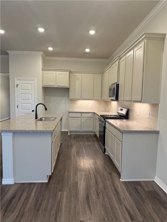 6308 Raleigh Drive College Station, TX 77845 - Photo 4 of 19 Kitchen featuring light stone counters, appliances with stainless steel finishes, crown molding, decorative backsplash, and a center island with sink
