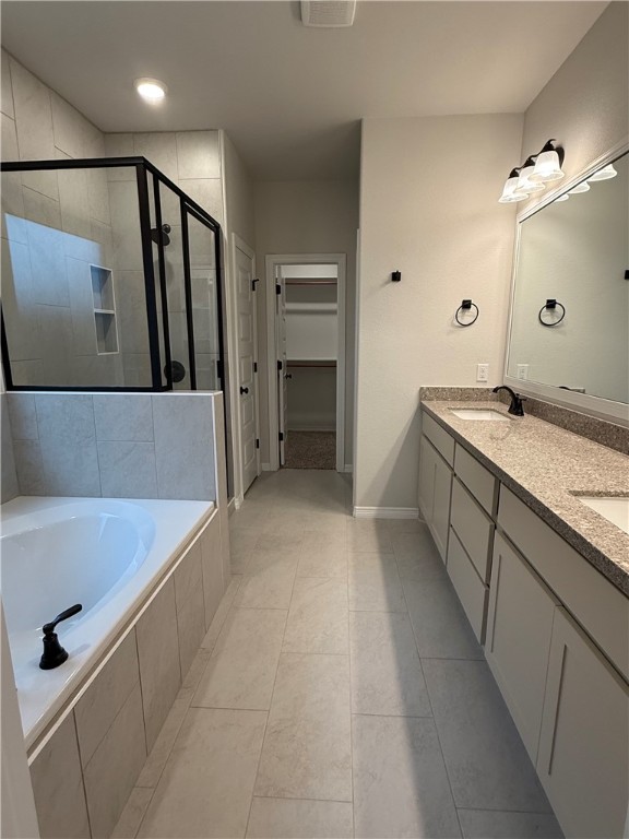 6308 Raleigh Drive College Station, TX 77845 - Photo 7 of 19 Full bath featuring a spacious closet, double vanity, a shower stall, a garden tub, and light tile patterned floors