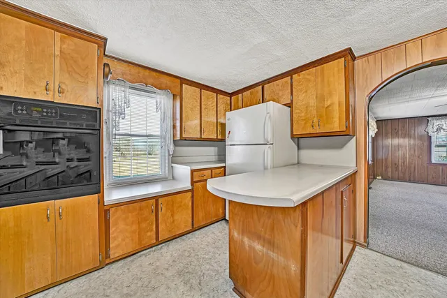 a kitchen with a sink a refrigerator and a view of living room