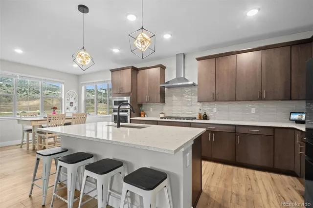 a kitchen with stainless steel appliances granite countertop a sink a stove a refrigerator cabinets and chairs