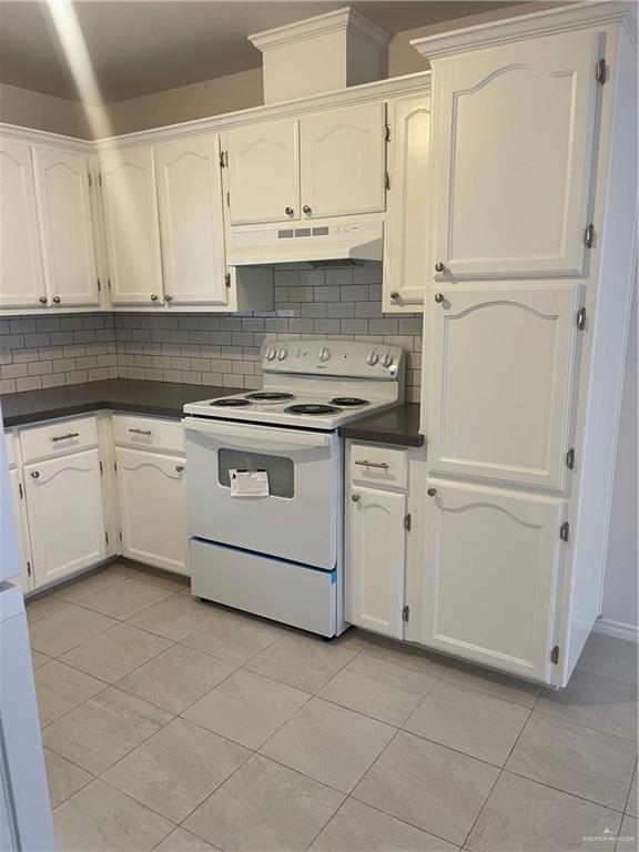1408 Pine Street, Unit C Weslaco, TX 78596 - Photo 4 of 9 Kitchen featuring electric range, dark countertops, tasteful backsplash, white cabinets, and extractor fan