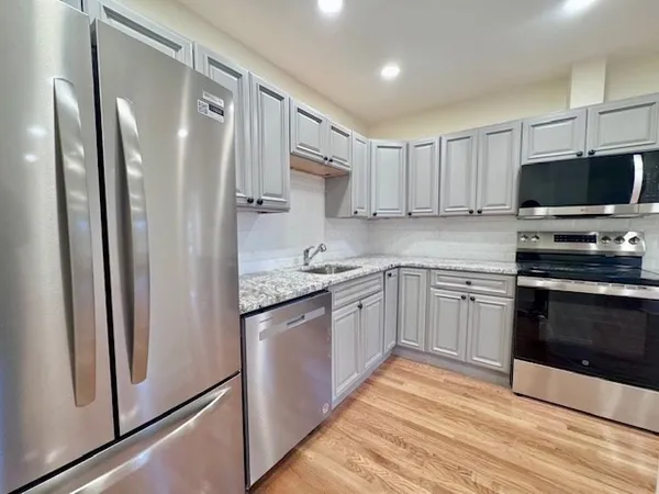 a kitchen with stainless steel appliances granite countertop a refrigerator sink and stove