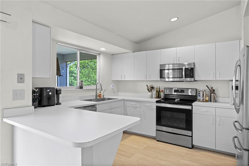 8366 Cardinal Road Fort Myers, FL 33967 - Photo 10 of 25 a kitchen with stainless steel appliances white cabinets and wooden floors
