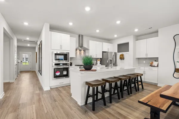 a kitchen with granite countertop a refrigerator a stove a sink and white cabinets