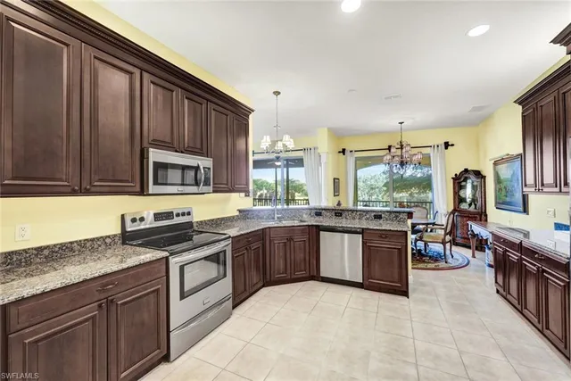 a large kitchen with stainless steel appliances granite countertop a stove top oven a sink dishwasher a dining table and chairs with wooden floor