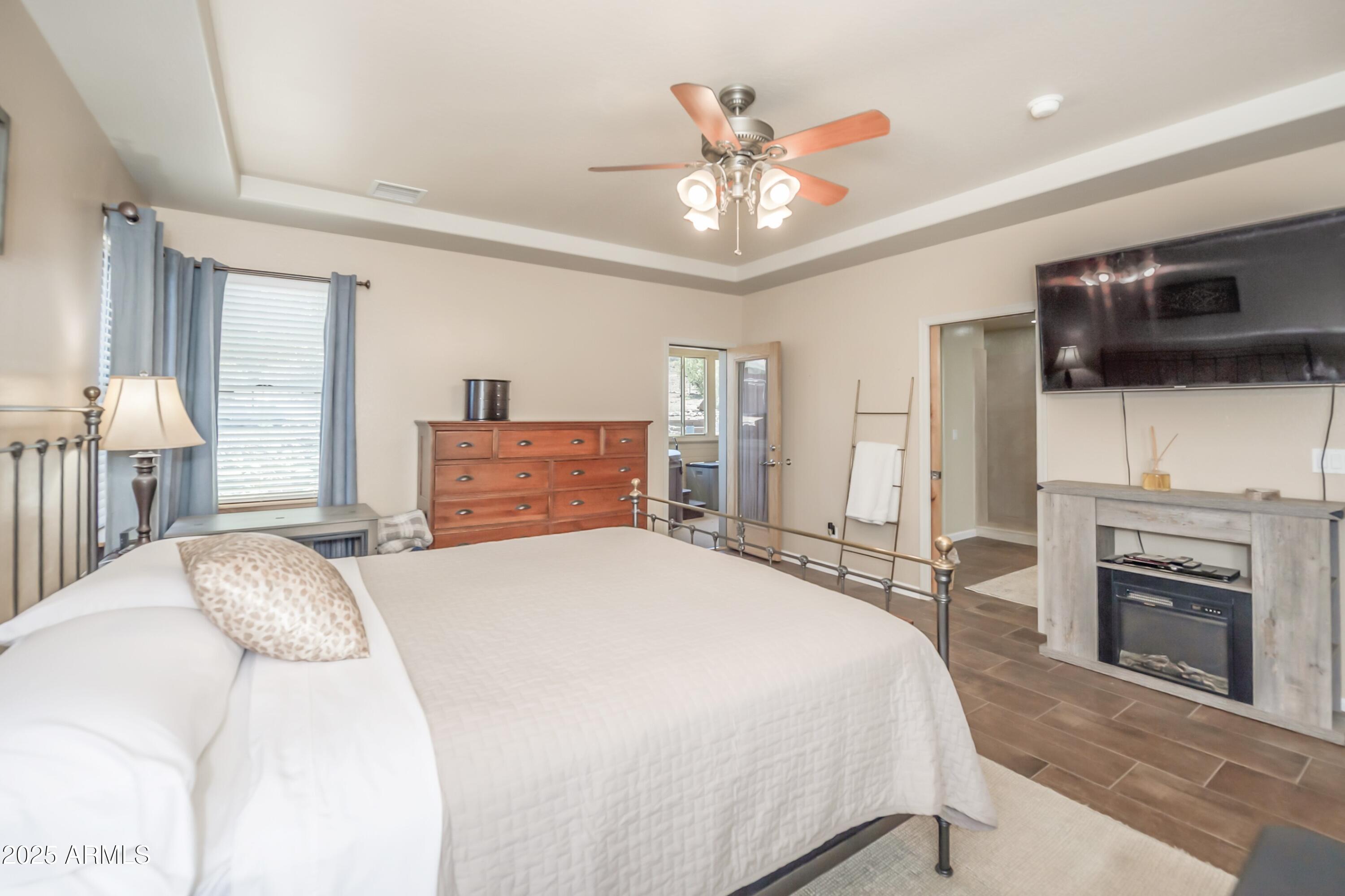 171 South Enchanted Road Dewey, AZ 86327 - Photo 15 of 62 a spacious bedroom with a large bed a flat tv screen and a fireplace with wooden floor