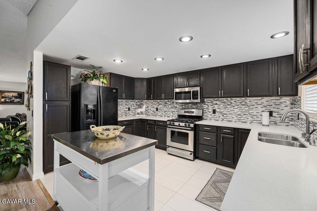 44115 Hunter Court Lancaster, CA 93536 - Photo 10 of 23 a kitchen with granite countertop stainless steel appliances a sink stove refrigerator and cabinets