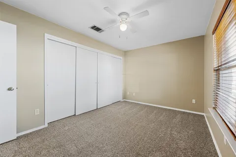 an empty room with windows and fan
