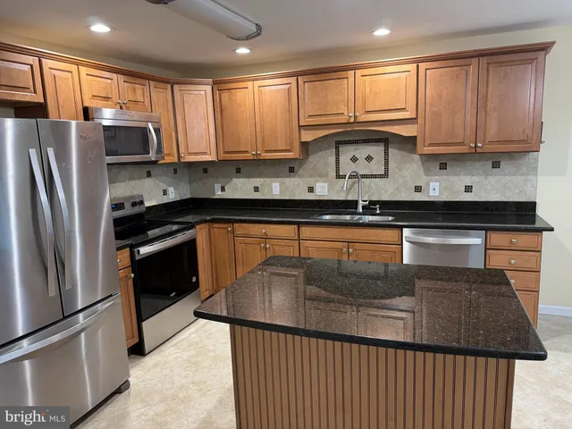 a kitchen with stainless steel appliances granite countertop a stove a sink dishwasher a refrigerator and cabinets with wooden floor