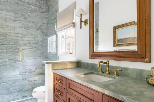 a bathroom with a granite countertop sink toilet and mirror