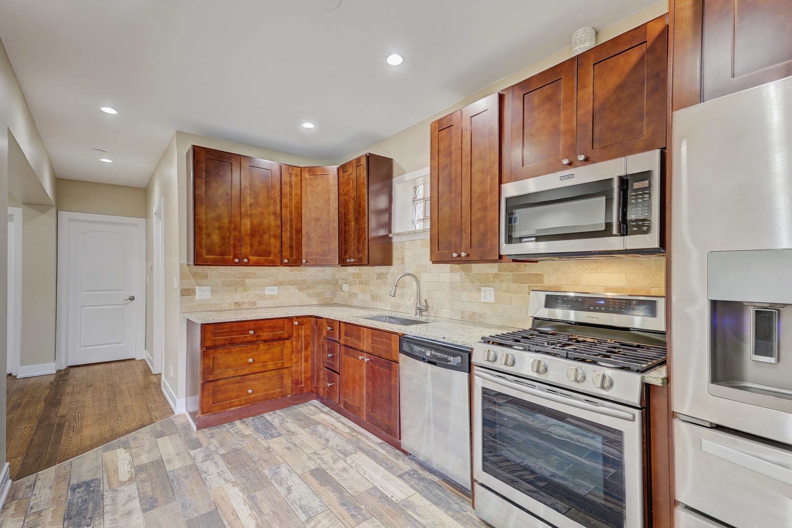 5040 West Berenice Avenue, Unit 1 Chicago, IL 60641 - Photo 8 of 18 a kitchen with stainless steel appliances granite countertop a stove a sink and a microwave