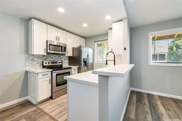 a kitchen with kitchen island a sink appliances and cabinets