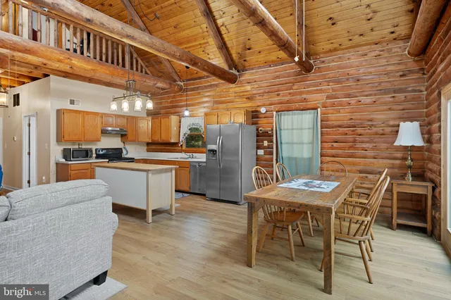 a dining hall with stainless steel appliances granite countertop a stove a sink a dining table and chairs with wooden floor