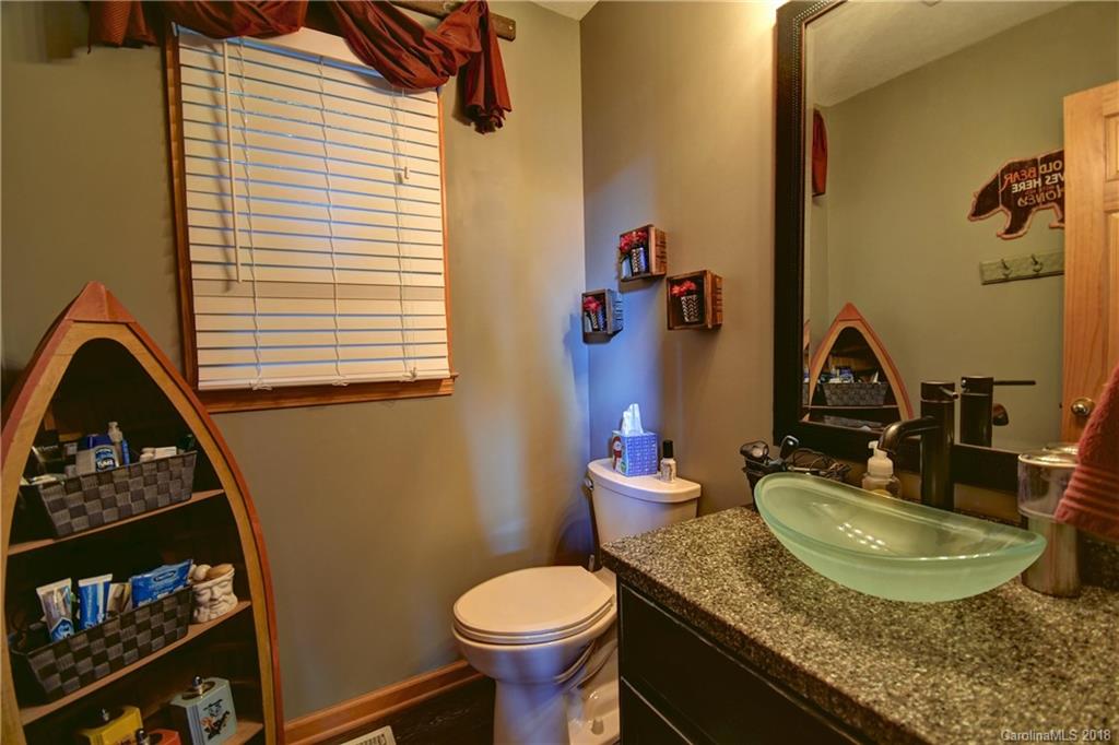 204 Kings Ridge Road Maggie Valley, NC 28751 - Photo 11 of 34 a bathroom with a granite countertop toilet a sink and a mirror