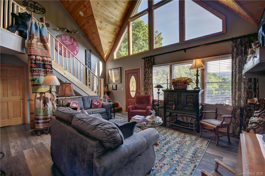 204 Kings Ridge Road Maggie Valley, NC 28751 - Photo 7 of 34 a living room with furniture a fireplace and large windows