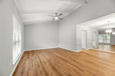 an empty room with wooden floor fan and windows