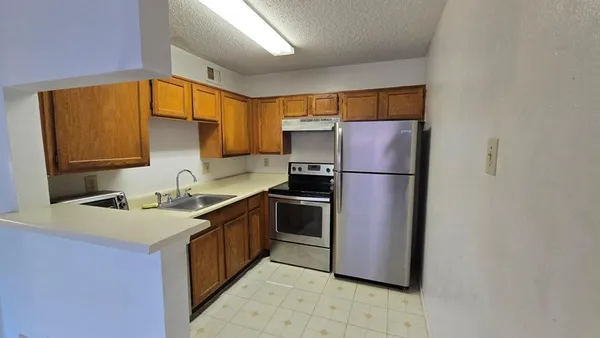 a kitchen with a sink a refrigerator and a stove top oven
