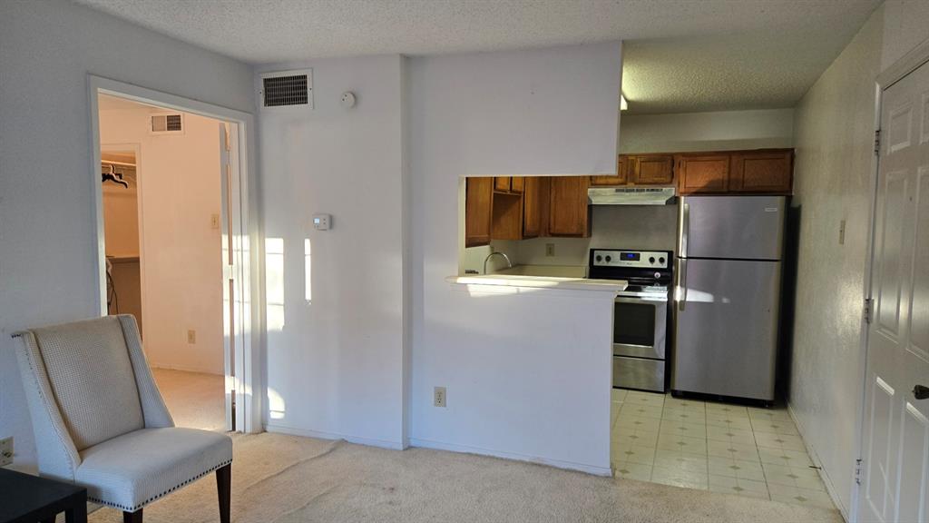 18333 Roehampton Drive, Unit 1028 Dallas, TX 75252 - Photo 3 of 8 a kitchen with a refrigerator a couch and chairs