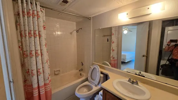 a bathroom with a sink a toilet and shower a mirror
