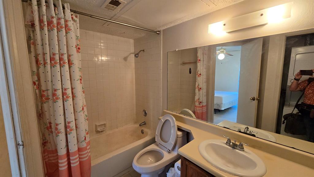 18333 Roehampton Drive, Unit 1028 Dallas, TX 75252 - Photo 5 of 8 a bathroom with a sink a toilet and shower a mirror