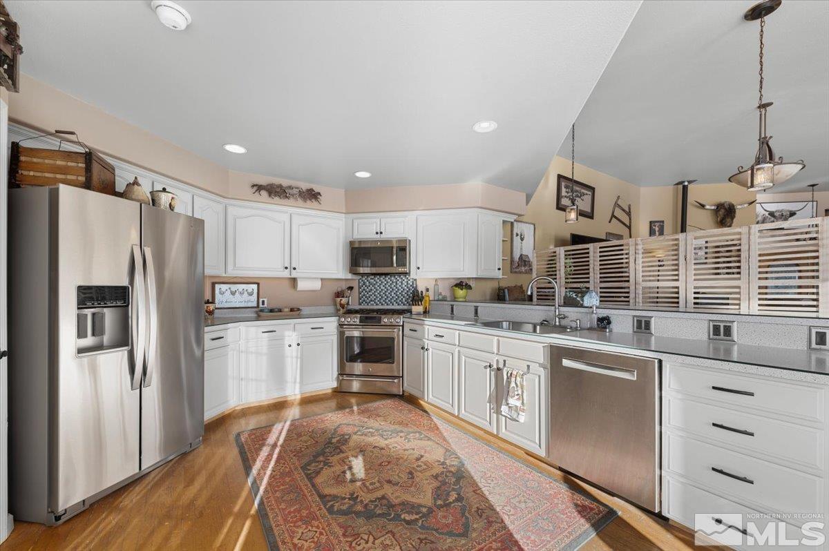 12803 North Red Rock Road Reno, NV 89508 - Photo 12 of 40 a kitchen with stainless steel appliances granite countertop a refrigerator a sink dishwasher a stove and white cabinets with wooden floor