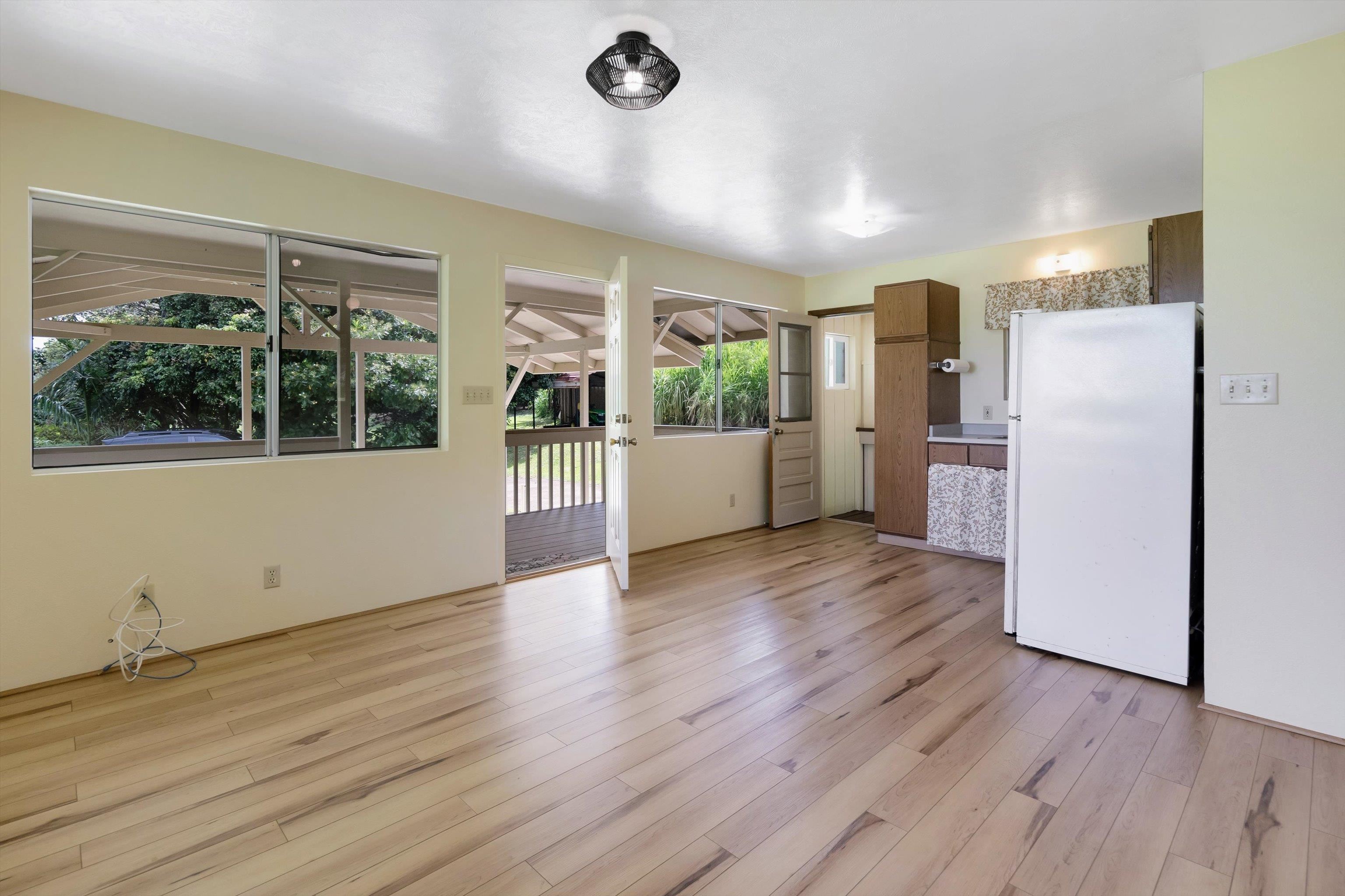 1784 West Kuiaha Road Haiku, HI 96708 - Photo 10 of 27 a view of a refrigerator in kitchen and an empty room with wooden floor