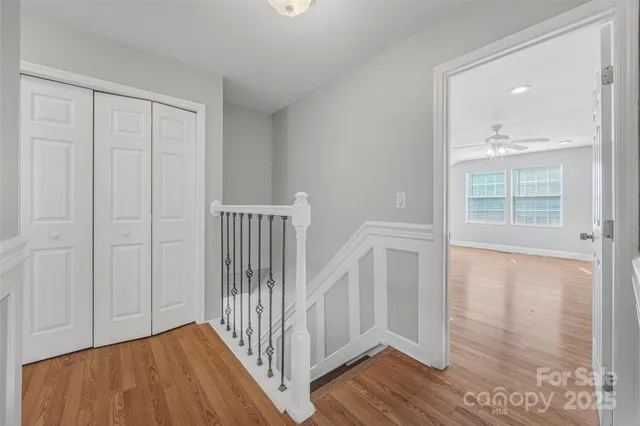 a view of empty room with wooden floor and fan