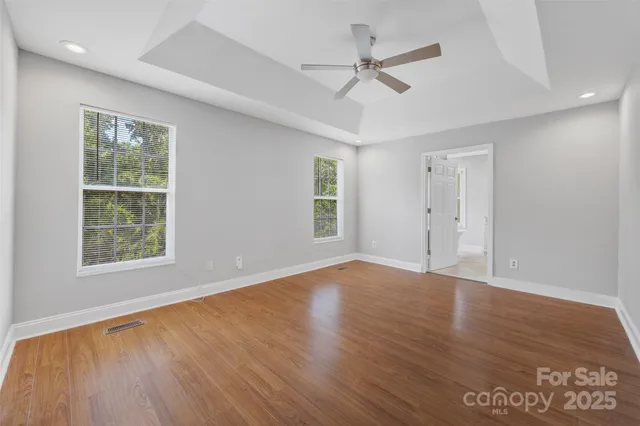 an empty room with wooden floor and ceiling fan