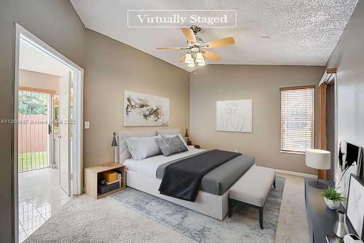 15540 Southwest 156th Avenue Miami, FL 33187 - Photo 3 of 37 a bedroom with a large bed and a chandelier