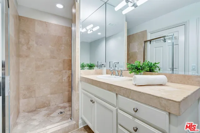 a bathroom with a granite countertop sink a mirror and a shower