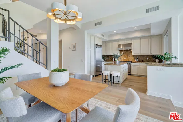 a kitchen with stainless steel appliances kitchen island granite countertop a dining table chairs and a coffee table