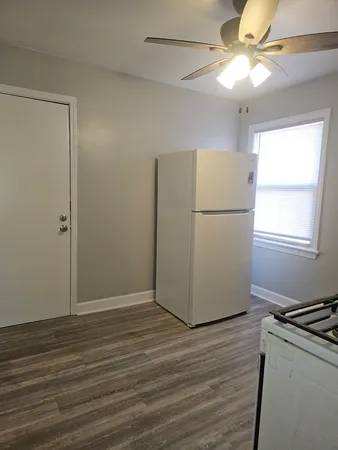 a view of a kitchen with a refrigerator a ceiling fan and wooden floor
