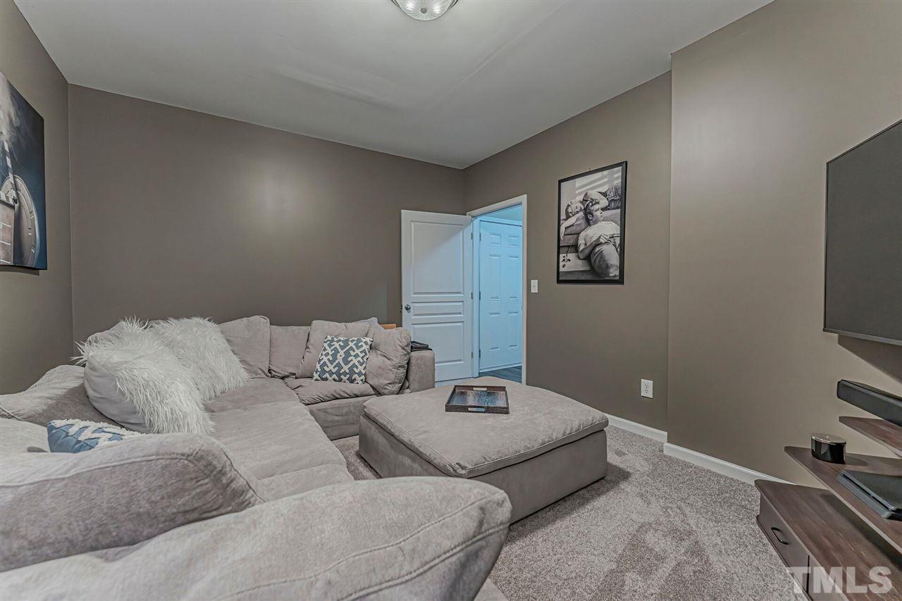5903 Hourglass Court Raleigh, NC 27612 - Photo 27 of 29 a living room with a couch and a flat screen tv