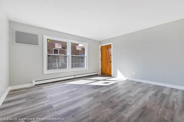 a view of empty room with wooden floor and fan