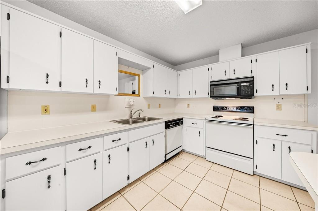 9377 Southwest 90th Court, Unit E Ocala, FL 34481 - Photo 21 of 77 a kitchen with granite countertop white cabinets and white appliances