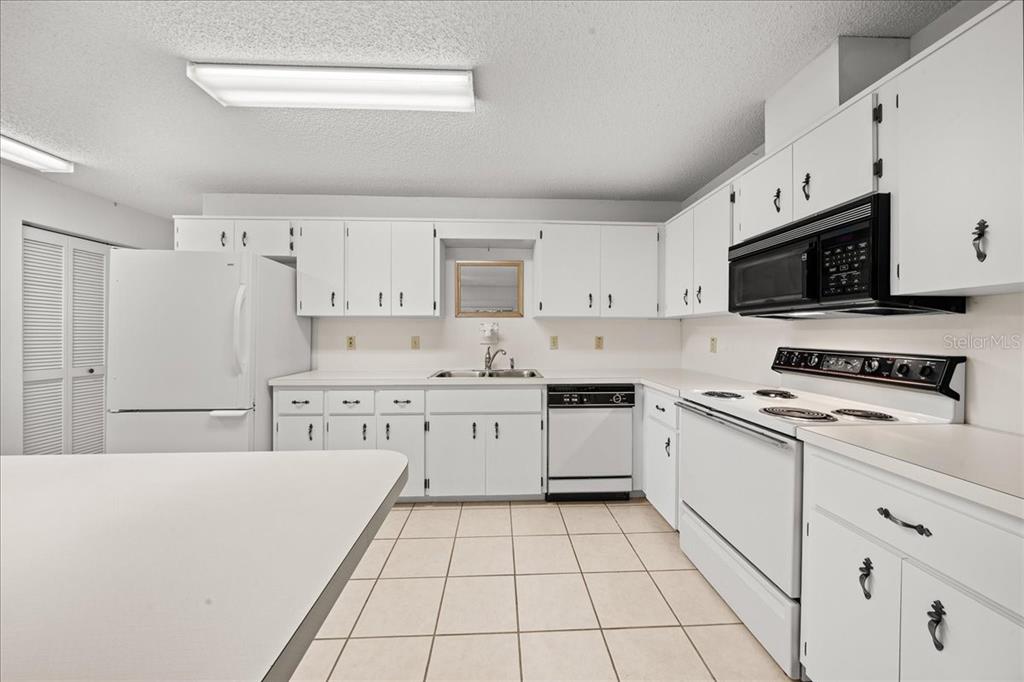 9377 Southwest 90th Court, Unit E Ocala, FL 34481 - Photo 22 of 77 a kitchen with kitchen island white cabinets a sink a stove a oven with a dining table and chairs