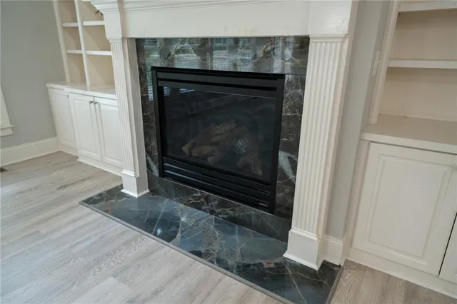 an empty room with wooden floor fireplace and windows