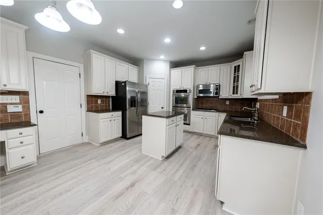 a kitchen with stainless steel appliances a refrigerator sink and white cabinets