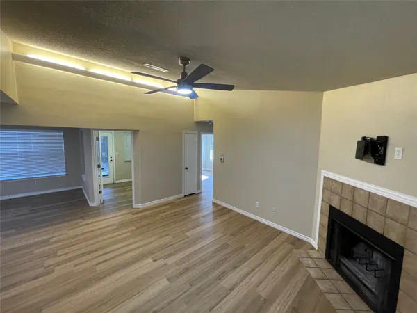 a view of an empty room with wooden floor fireplace and a window