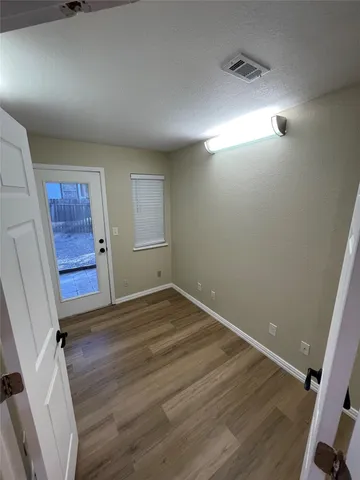 an empty room with wooden floor and window