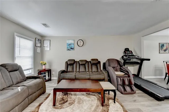 a living room with furniture a rug and gym equipment