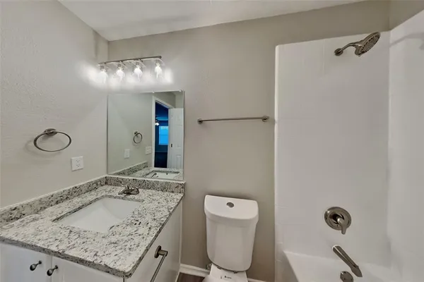 a bathroom with a granite countertop sink a toilet and a mirror