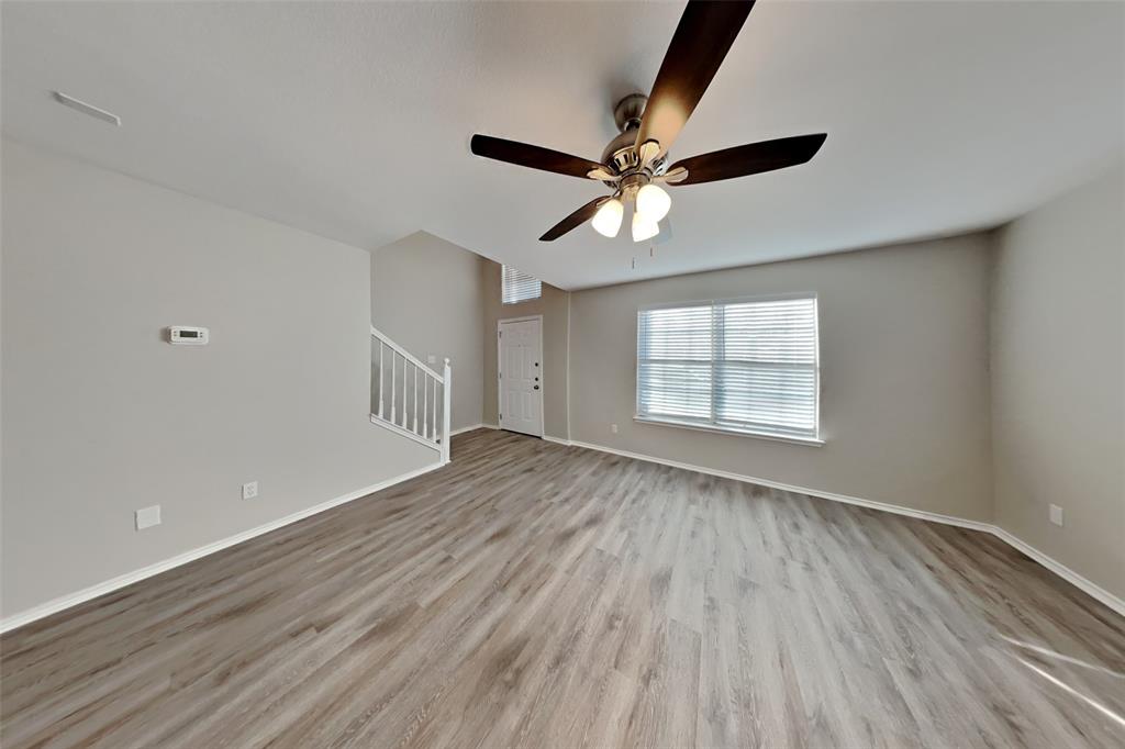 3925 Cane River Road Fort Worth, TX 76244 - Photo 2 of 21 Unfurnished living room featuring light wood-style floors, ceiling fan, and stairs