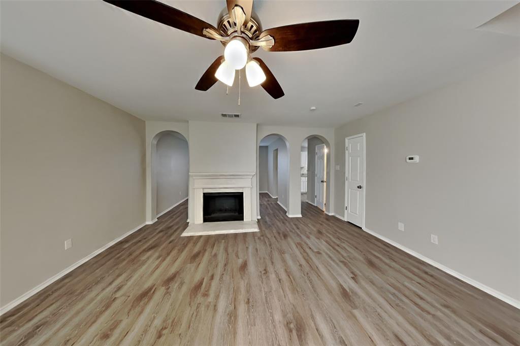 3925 Cane River Road Fort Worth, TX 76244 - Photo 3 of 21 Unfurnished living room featuring a fireplace with raised hearth, light wood-style floors, and a ceiling fan