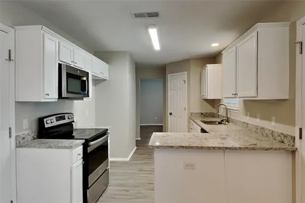 a kitchen with granite countertop a sink a stove and cabinets