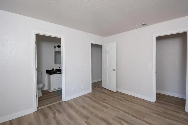 a view of an empty room with wooden floor & closet