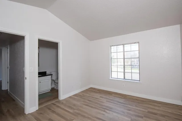 an empty room with wooden floor closet and windows