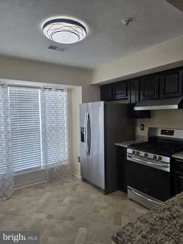 a view of kitchen with refrigerator and cabinets